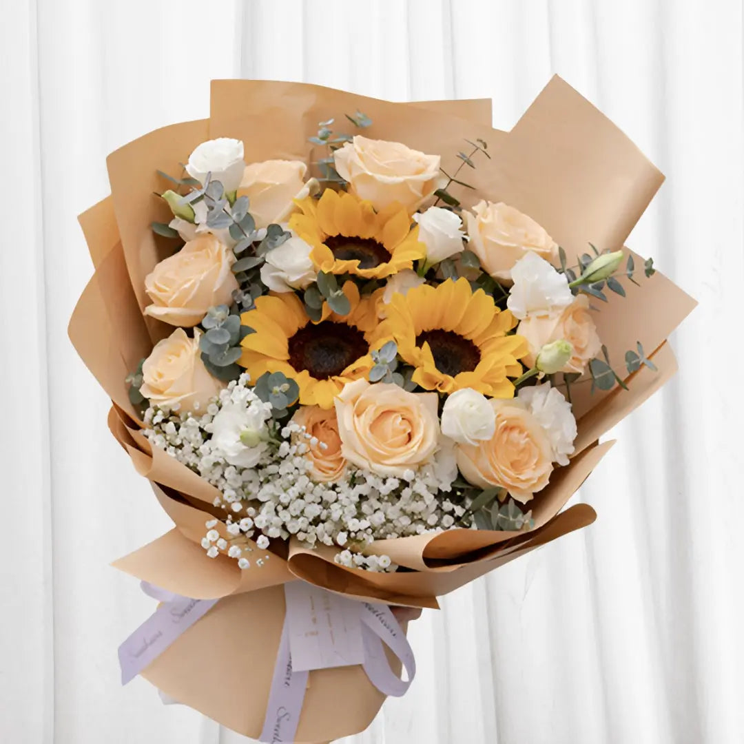 Sunshine Serenity Bouquet with sunflowers, peach roses, white roses, baby’s breath, and eucalyptus.