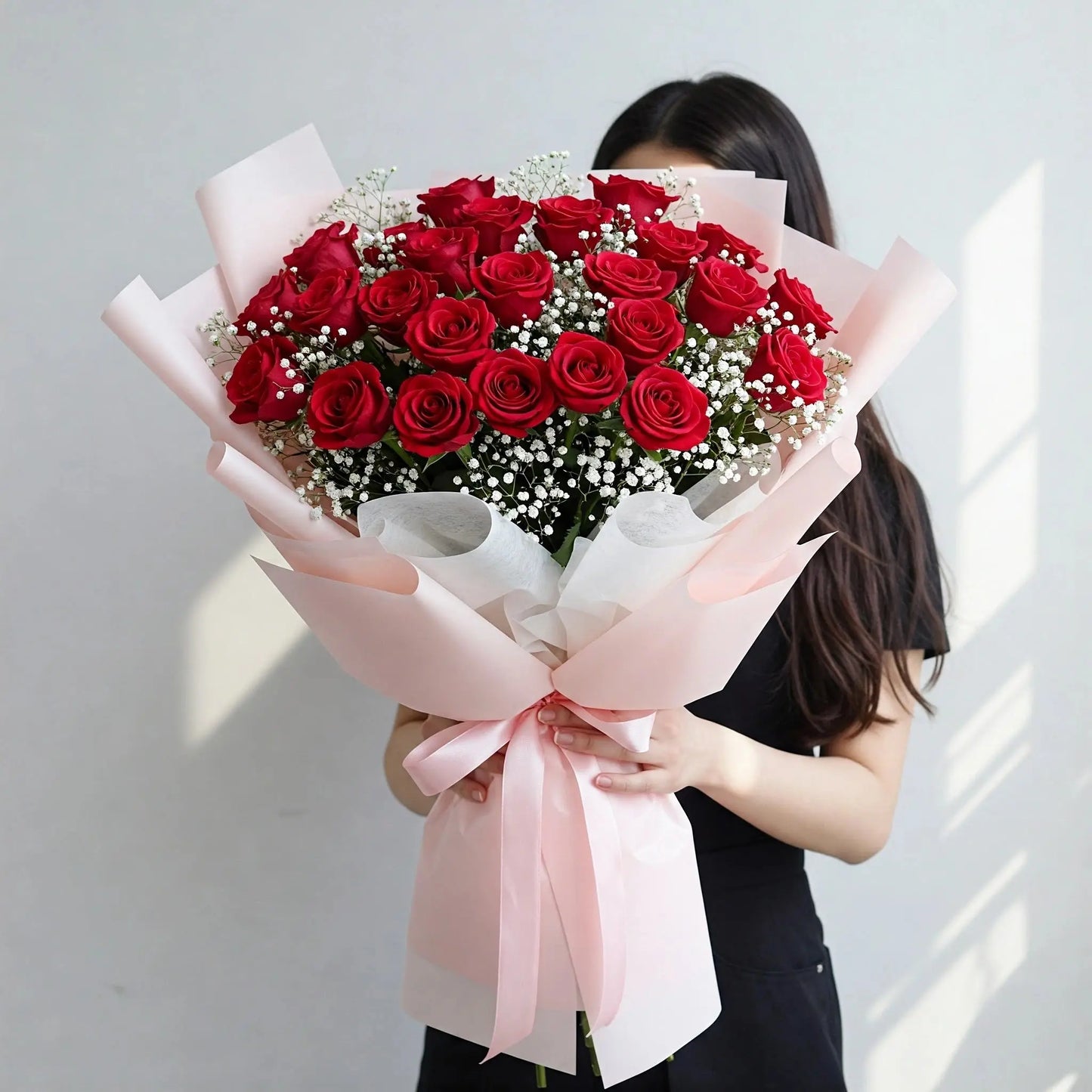 A captivating bouquet of 30 red roses adorned with baby's breath, wrapped in elegant white and pink paper, ready for flower delivery in Hong Kong.