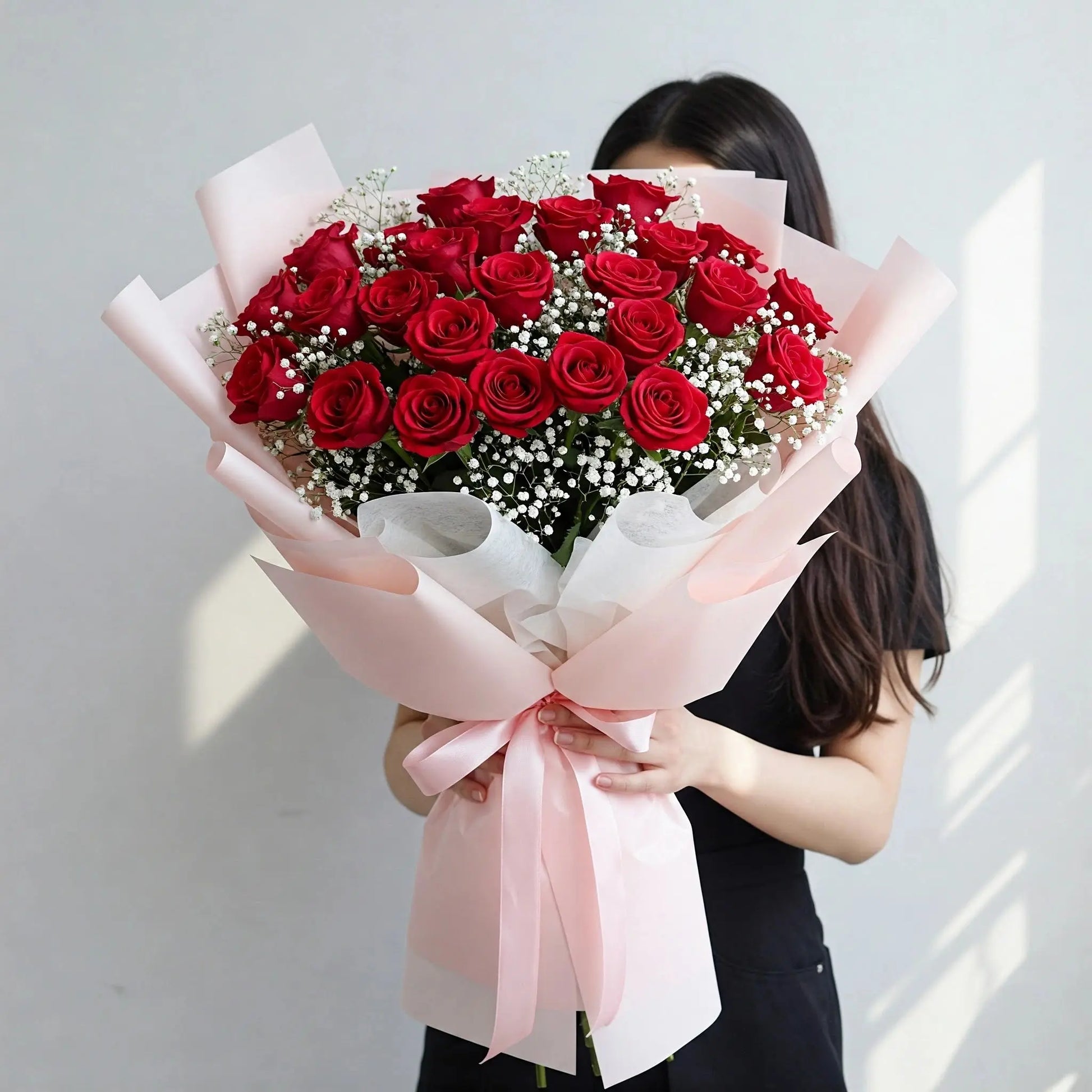 A captivating bouquet of 30 red roses adorned with baby's breath, wrapped in elegant white and pink paper, ready for flower delivery in Hong Kong.